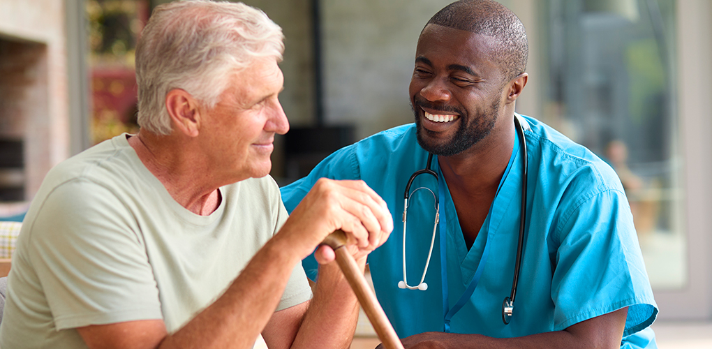 male nurse visiting senior man using walking stick with mobility issues home